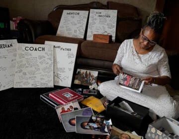 Carolyn Burnett sorts through mementos to select items to commemorate her son Chris Burnett Sunday, Dec. 5, 2021, in Olathe, Kan. Chris Burnett, who coached football at Olathe East High School, died of COVID-19 on Sept. 11 at The age of 34. (AP Photo/Charlie Riedel)