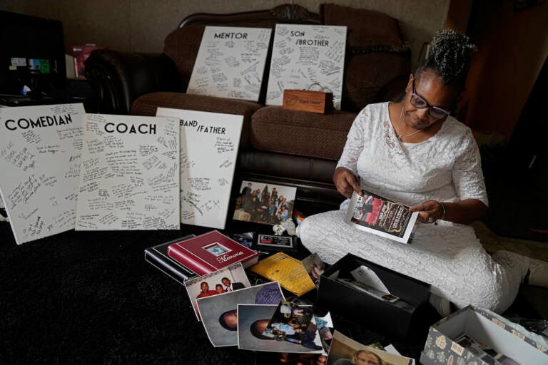 Carolyn Burnett sorts through mementos to select items to commemorate her son Chris Burnett Sunday, Dec. 5, 2021, in Olathe, Kan. Chris Burnett, who coached football at Olathe East High School, died of COVID-19 on Sept. 11 at The age of 34. (AP Photo/Charlie Riedel)