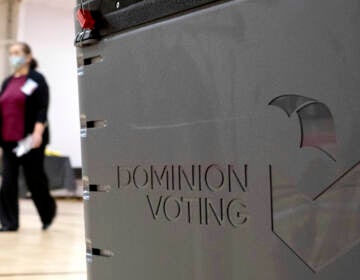 File photo: A worker passes a Dominion Voting ballot scanner while setting up a polling location at an elementary school in Gwinnett County, Ga., outside of Atlanta on Jan. 4, 2021. (AP Photo/Ben Gray, File)