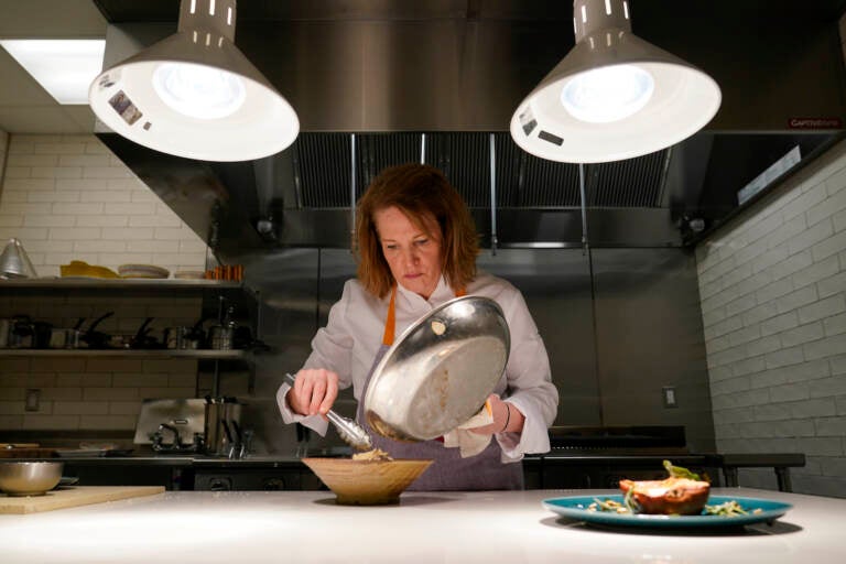 Amy Brandwein, chef and owner of Centrolina, prepares a dish in her restaurant kitchen, Thursday, Dec. 16, 2021, in Washington. While restaurants in the U.S. and United Kingdom are open without restrictions and often bustling, they are entering their second winter of the coronavirus pandemic anxious about what’s ahead. (AP Photo/Patrick Semansky)
