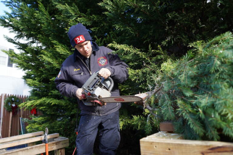 Gladwyne firefighters offer the whole service during their Christmas tree sale, including some light touch-ups to even out the bottom of trees before they find their way to new homes