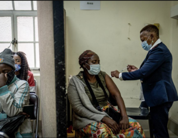 A woman is vaccinated against COVID-19 at the Hillbrow Clinic in Johannesburg, South Africa, Monday Dec. 6, 2021. South African doctors say the rapid increase in COVID-19 cases attributed to the new omicron variant is resulting in mostly mild symptoms. (AP Photo/ Shiraaz Mohamed)