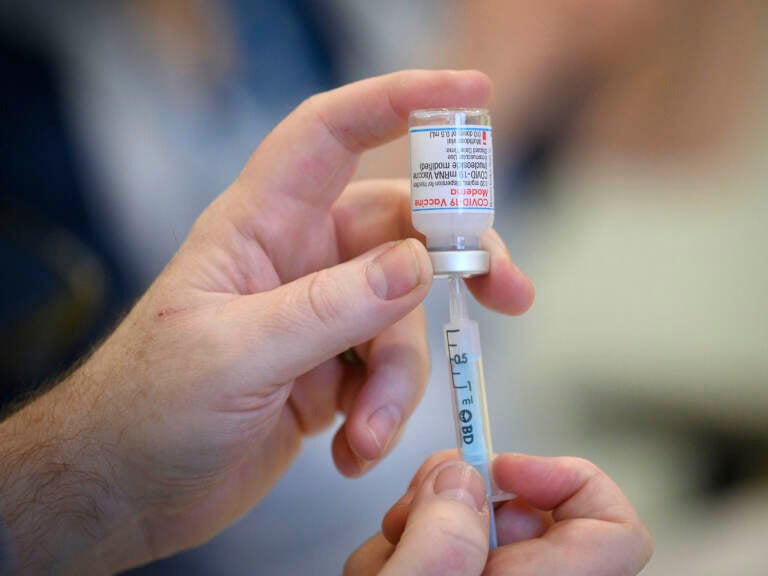 Medical staff and volunteers prepare shots of the Moderna COVID-19 vaccine