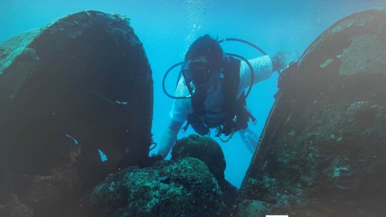 A member of Project Recovery combs through the debris of a downed aircraft found in the Pacific Ocean off Palau. (Project Recover)