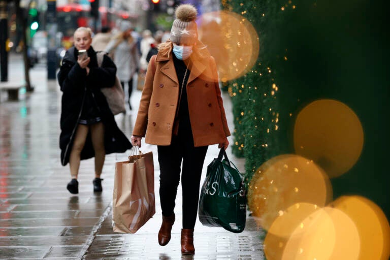 A woman wearing a face mask carries shopping bags along Oxford Street