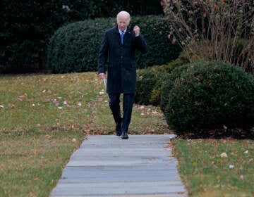 Biden walks down a path while removing his face mask