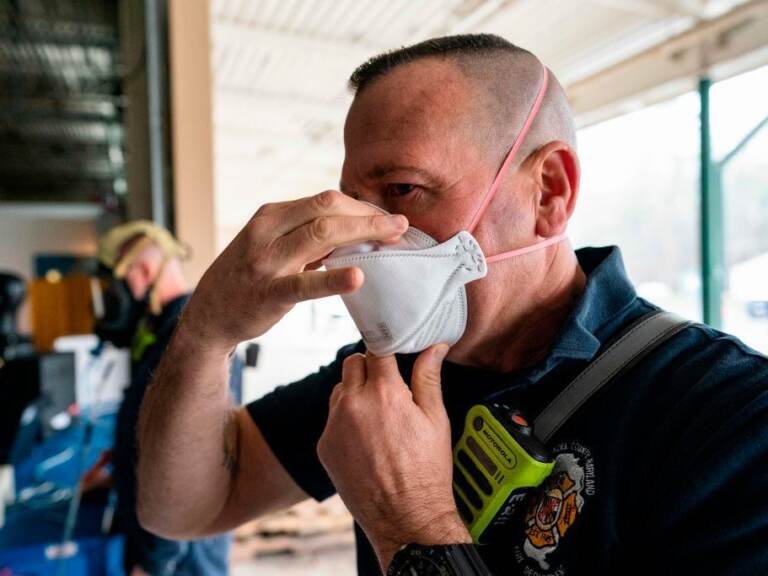 A firefighter tests the seal on his N95 mas