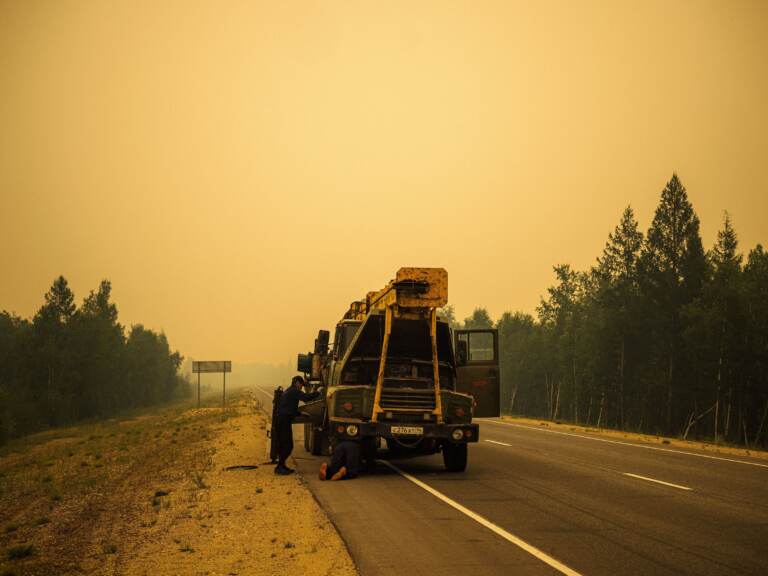 Men repair their truck in smoke from a forest fire on a road near Magaras, in the republic of Sakha, Siberia, in July. (Dimitar Dilkoff/AFP via Getty Images)