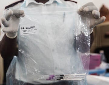 A health care worker holds doses of J&J vaccines