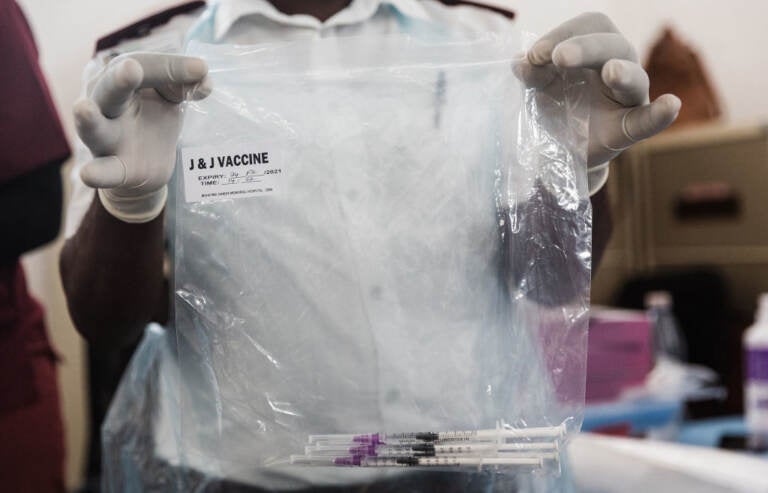 A health care worker holds doses of J&J vaccines