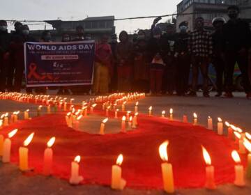 Volunteers stand after lighting candles in the shape of a red ribbon during an awareness event ahead of World AIDS Day in Kathmandu on Tuesday. (Prakash Mathema/AFP via Getty Images)