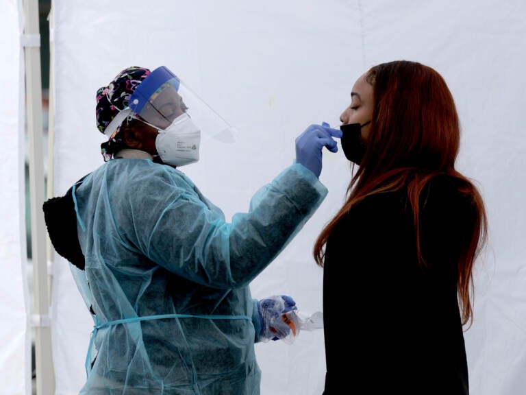 A healthcare worker administers a COVID-19 PCR test at a free test site in Farragut Square on December 28, 2021 in Washington, DC. (Photo by Anna Moneymaker/Getty Images)