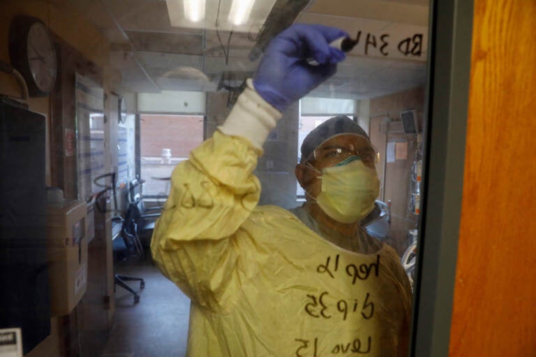 U.S. Army Critical Care Nurse Captain Edward Rauch Jr. writes on the room door of a COVID-19 patient