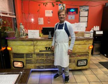 Jagdeep Nayyar, owner and chef at My Taste of India, stands in front of the register stand that's made from the front panel of a real Tata truck — the best-selling brand in India. (Joel Rose/Joel Rose)