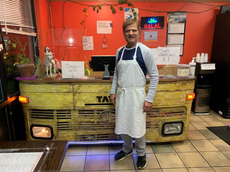 Jagdeep Nayyar, owner and chef at My Taste of India, stands in front of the register stand that's made from the front panel of a real Tata truck — the best-selling brand in India. (Joel Rose/Joel Rose)