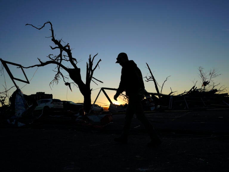 APTOPIX Midwest Tornadoes A cleanup worker walks past damaged trees
