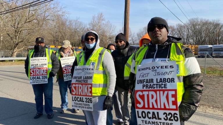 Striking bus drivers with Teamsters Local 326 stand outside the First Student bus yard