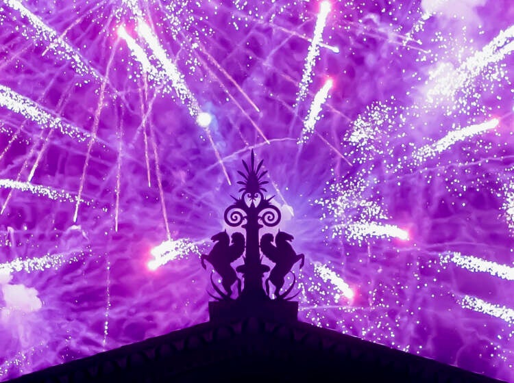 Fireworks explode in the background behind a gargoyle atop of the central portico of the Philadelphia Museum of Art