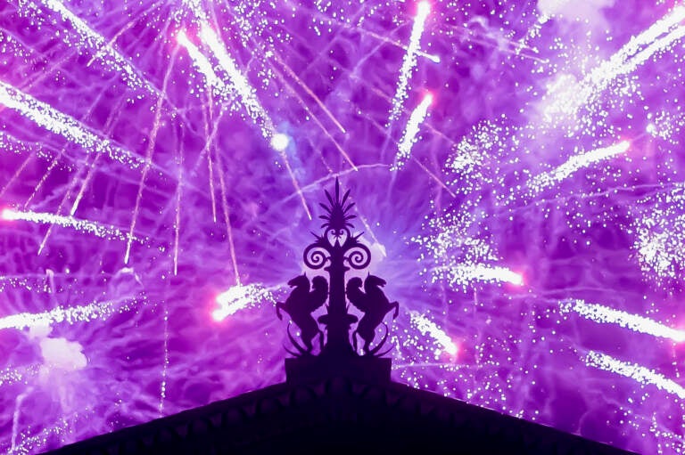 Fireworks explode in the background behind a gargoyle atop of the central portico of the Philadelphia Museum of Art