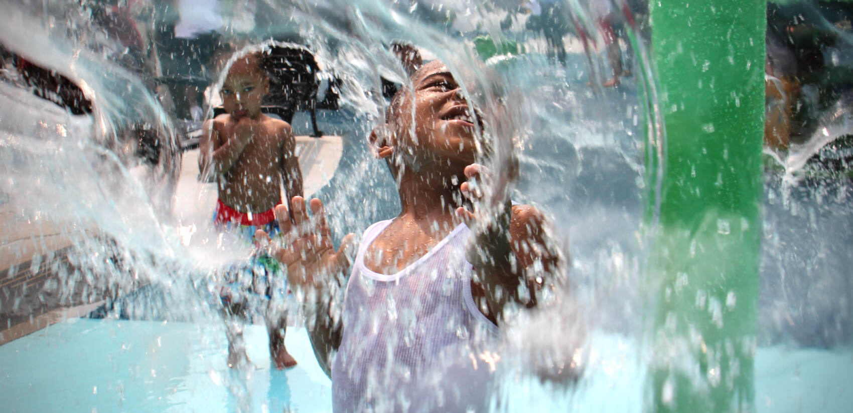 Mesiah Clark, 4, cools off at the newly reopened 8th and Diamond Playground. (Emma Lee/WHYY)