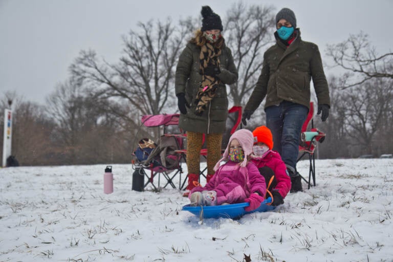 Natasha Mell-Taylor and Jared Greenwald watch their 5-year-old Juniper and her friend Phoebe sled at Fairmount Park