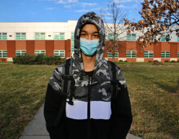 Ali Wahaj Mosakhil wears a mask while standing in front of a school
