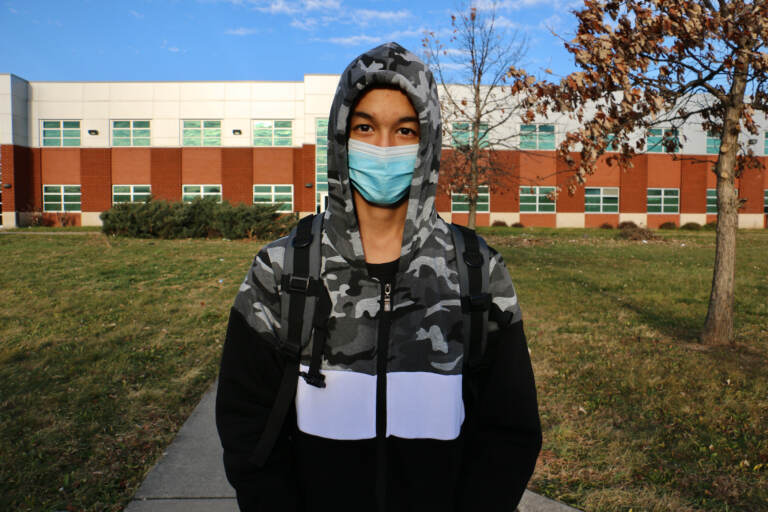 Ali Wahaj Mosakhil wears a mask while standing in front of a school