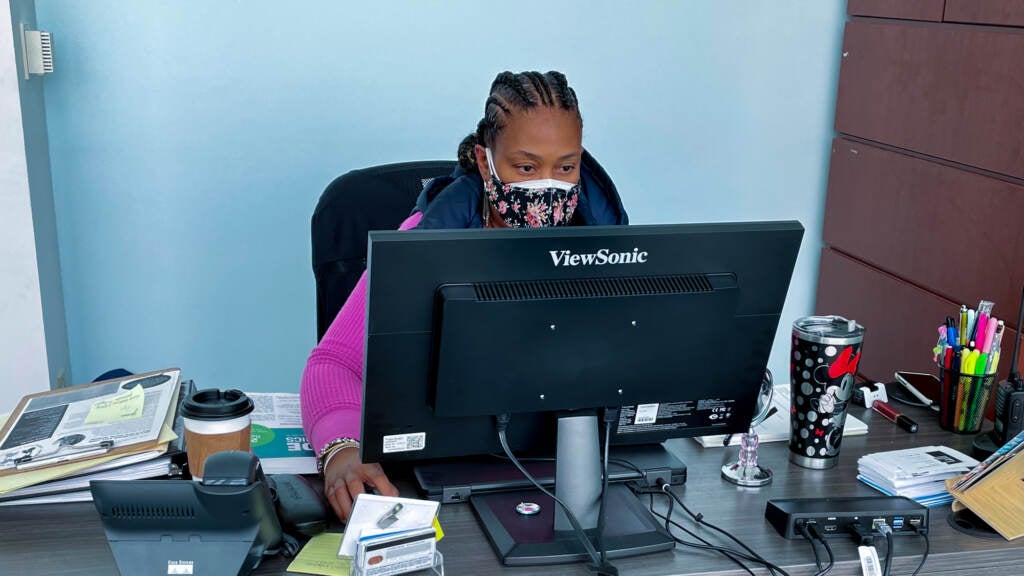 Yanna McGraw sits behind a desk while wearing a mask