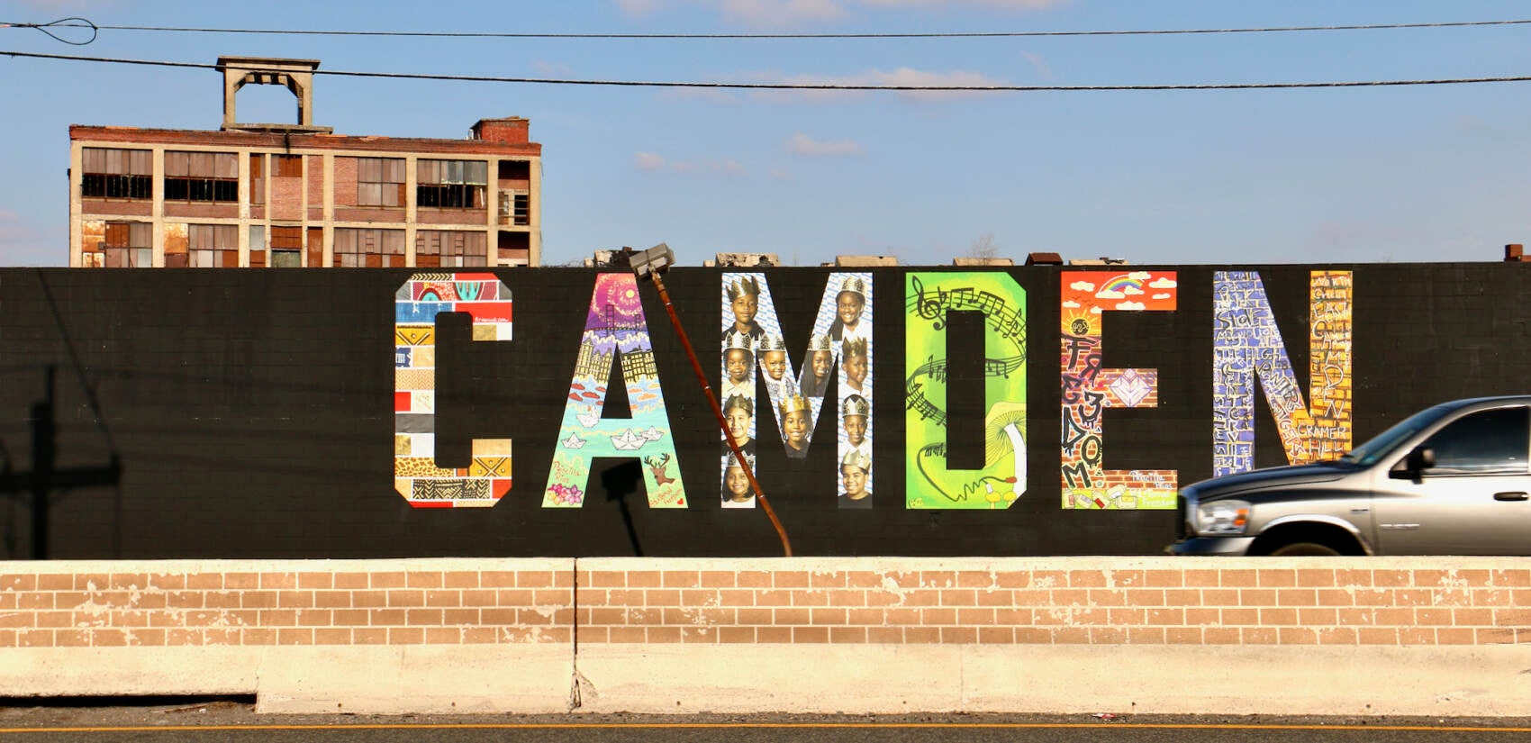 The ''Camden Invincible'' mural fronts on Admiral Wilson Boulevard, one of the most-traveled roads in South Jersey. (Emma Lee/WHYY)