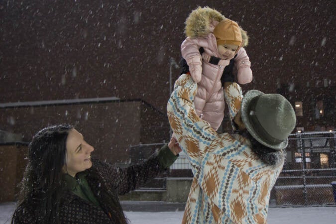 5 month-old Claudia plays in the snow with her mom, Sage, and dad, Bacho, for the first time at Palumbo Recreation Center in South Philadelphia on Jan. 28, 2022. (Kimberly Paynter/WHYY)