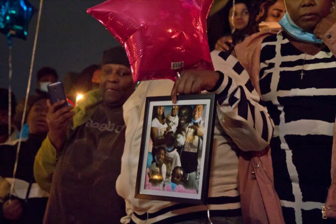 Family members of those that died in the Fairmount row home fire held pictures of their lost loved-ones at a candlelight vigil at 22nd and Brown Streets in Philadelphia on Jan. 6, 2022. (Kimberly Paynter/WHYY)