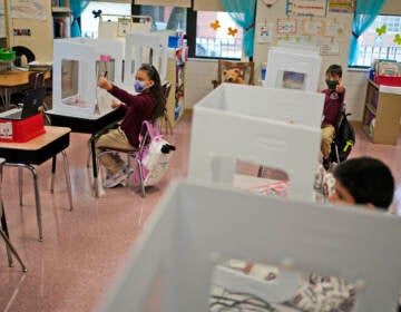 Third graders do their work behind see-though partitions at Christa McAuliffe School in Jersey City, N.J., Thursday, April 29, 2021. (AP Photo/Seth Wenig)