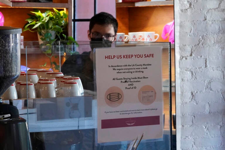 A sign explaining the LA County Mandate is posted for customers inside the Intelligentsia Coffee in Sunset Blvd., coffee shop in Los Angeles, Monday, Nov. 29, 2021.  (AP Photo/Damian Dovarganes)