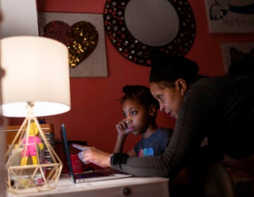 Abigail Schneider, 8, center, completes a level of her learning game with her mother April in her bedroom, Wednesday, Dec. 8, 2021, in the Brooklyn borough of New York. 