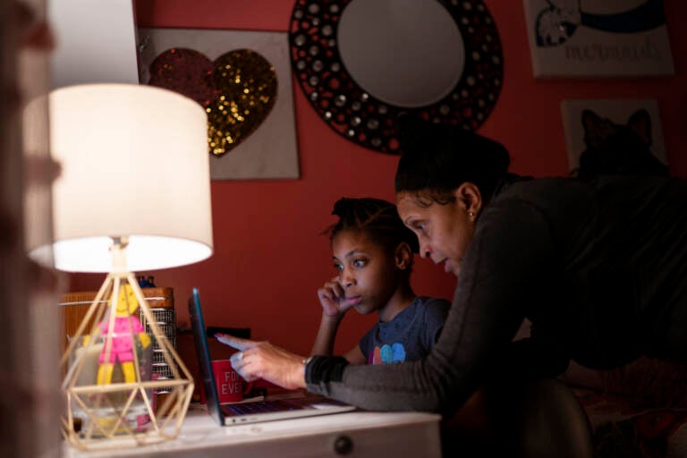 Abigail Schneider, 8, center, completes a level of her learning game with her mother April in her bedroom, Wednesday, Dec. 8, 2021, in the Brooklyn borough of New York. 