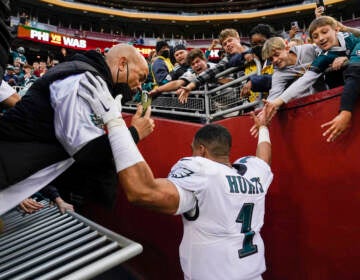 A hand railing collapses and fans fall onto Philadelphia Eagles quarterback Jalen Hurts (1) following the end of an NFL football game, Sunday, Jan. 2, 2022, in Landover, Md. Philadelphia won 20-16. (AP Photo/Alex Brandon)