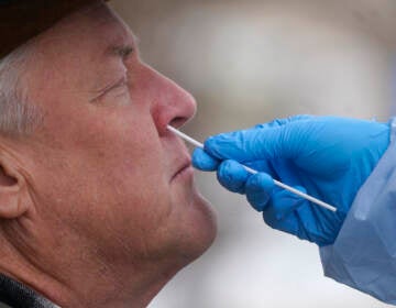 A member of the Salt Lake County Health Department COVID-19 testing staff performs a test on Gary Mackelprang outside the Salt Lake County Health Department Tuesday, Jan. 4, 2022, in Salt Lake City