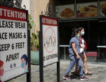 File - In this June 11, 2021 file photo customers wear face masks in an outdoor mall with closed business amid the COVID-19 pandemic in Los Angeles. Coronavirus cases have jumped 500% in Los Angeles County over the past month and health officials warned Tuesday, July 13, 2021, that the especially contagious delta variant of the disease continues to spread rapidly among California's unvaccinated population. (AP Photo/Damian Dovarganes,File)