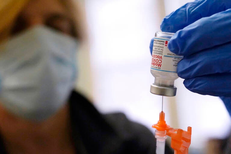 Pharmacist Kenni Clark prepares a booster dose of the Moderna COVID-19 vaccine during a vaccination clinic at City of Lawrence's 