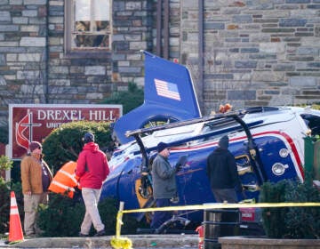 A medical helicopter rests next to the Drexel Hill United Methodist Church after it crashed in the Drexel Hill section of Upper Darby, Pa., on Wednesday, Jan. 12, 2022. Authorities and a witness say a pilot crash landed a medical helicopter without casualties in a residential area of suburban Philadelphia, miraculously avoiding a web of power lines and buildings as the aircraft fluttered, hit the street and slid into bushes outside a church.(AP Photo/Matt Rourke)