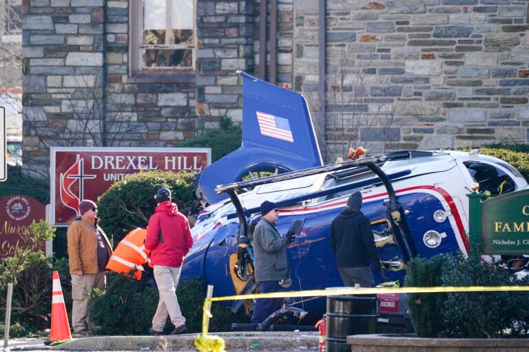 A medical helicopter rests next to the Drexel Hill United Methodist Church after it crashed in the Drexel Hill section of Upper Darby, Pa., on Wednesday, Jan. 12, 2022. Authorities and a witness say a pilot crash landed a medical helicopter without casualties in a residential area of suburban Philadelphia, miraculously avoiding a web of power lines and buildings as the aircraft fluttered, hit the street and slid into bushes outside a church.(AP Photo/Matt Rourke)