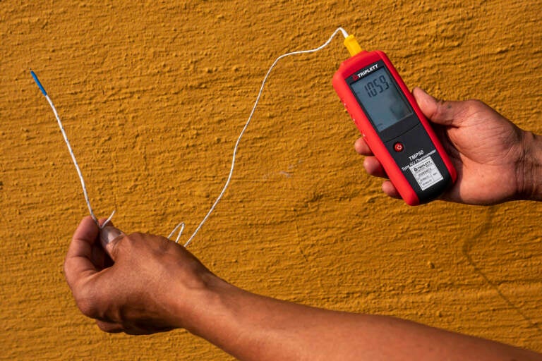 Vivek Shandas, a professor of climate adaptation at Portland State University, takes a temperature reading of almost 106 degrees in downtown Thursday, Aug. 12, 2021, in Portland, Ore. People have headed to cooling centers as the Pacific Northwest began sweltering under another major, multiday heat wave. (AP Photo/Nathan Howard)