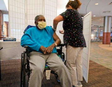 Edward Williams, 62, a resident at the Hebrew Home at Riverdale, receives a COVID-19 booster shot in New York, Sept. 27, 2021. COVID-19 infections are soaring again at U.S. nursing homes because of the omicron wave, and deaths are climbing too. That's leading to new restrictions on family visits and a renewed push to get more residents and staff members vaccinated and boosted. (AP Photo/Seth Wenig, File)