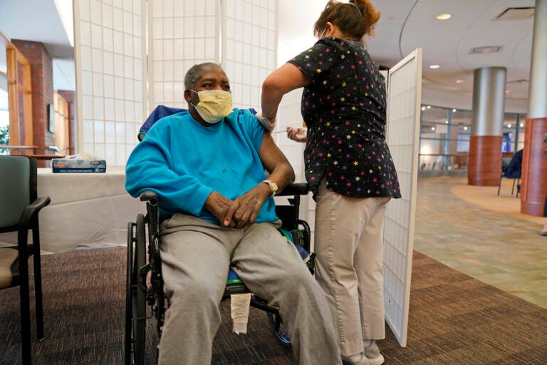 Edward Williams, 62, a resident at the Hebrew Home at Riverdale, receives a COVID-19 booster shot in New York, Sept. 27, 2021. COVID-19 infections are soaring again at U.S. nursing homes because of the omicron wave, and deaths are climbing too. That's leading to new restrictions on family visits and a renewed push to get more residents and staff members vaccinated and boosted. (AP Photo/Seth Wenig, File)