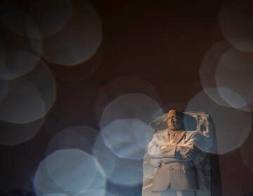 In a long exposure photo, lights from a snowplow illuminate sleet at the Martin Luther King Jr. Memorial in Washington, Sunday, Jan. 16, 2022. Ceremonies scheduled for the site on Monday, to mark the Martin Luther King Jr. national holiday, have been canceled because of the weather. (AP Photo/Carolyn Kaster)