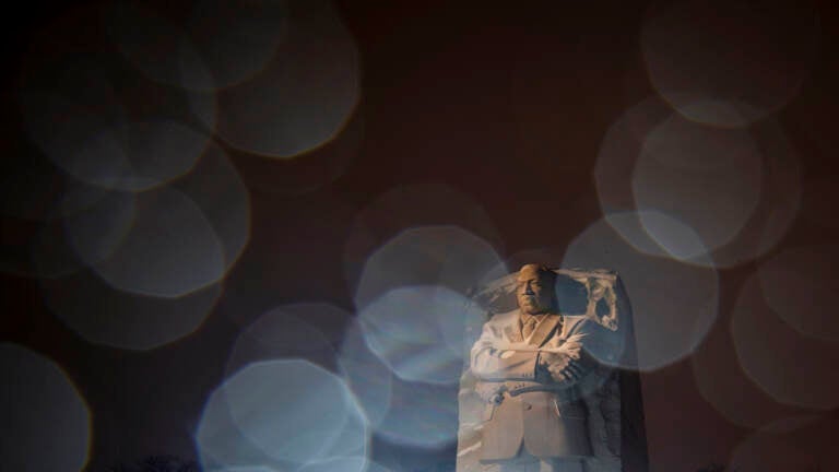 In a long exposure photo, lights from a snowplow illuminate sleet at the Martin Luther King Jr. Memorial in Washington, Sunday, Jan. 16, 2022. Ceremonies scheduled for the site on Monday, to mark the Martin Luther King Jr. national holiday, have been canceled because of the weather. (AP Photo/Carolyn Kaster)