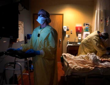 Registered nurse Shelly Girardin, left, is illuminated by the glow of a computer monitor as Dr. Shane Wilson examines COVID-19 patient Neva Azinger inside Scotland County Hospital in Memphis, Mo., on Nov. 24, 2020. (AP Photo/Jeff Roberson, File)