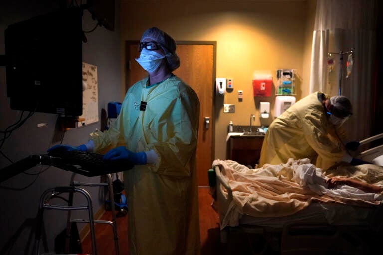 Registered nurse Shelly Girardin, left, is illuminated by the glow of a computer monitor as Dr. Shane Wilson examines COVID-19 patient Neva Azinger inside Scotland County Hospital in Memphis, Mo., on Nov. 24, 2020. (AP Photo/Jeff Roberson, File)
