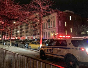Police secure the scene outside a six story residential building, left, where two NYPD officers where shot responding to a domestic disturbance call in Harlem, Friday Jan. 21, 2022, in New York