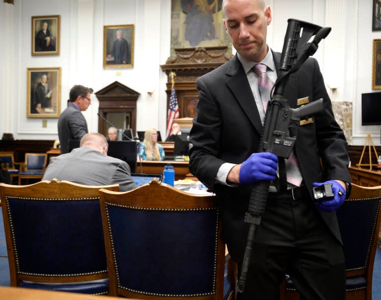 File photo: Kenosha Police Department Detective Martin Howard, right, picks up the weapon Kyle Rittenhouse used on Aug. 25, 2020, during Rittenhouse's trial at the Kenosha County Courthouse in Kenosha, Wis., on Nov. 8, 2021. A Wisconsin judge on Friday, Jan. 28, 2022, approved an agreement by lawyers to destroy the assault-style rifle that Rittenhouse used to shoot three people during a 2020 street protest